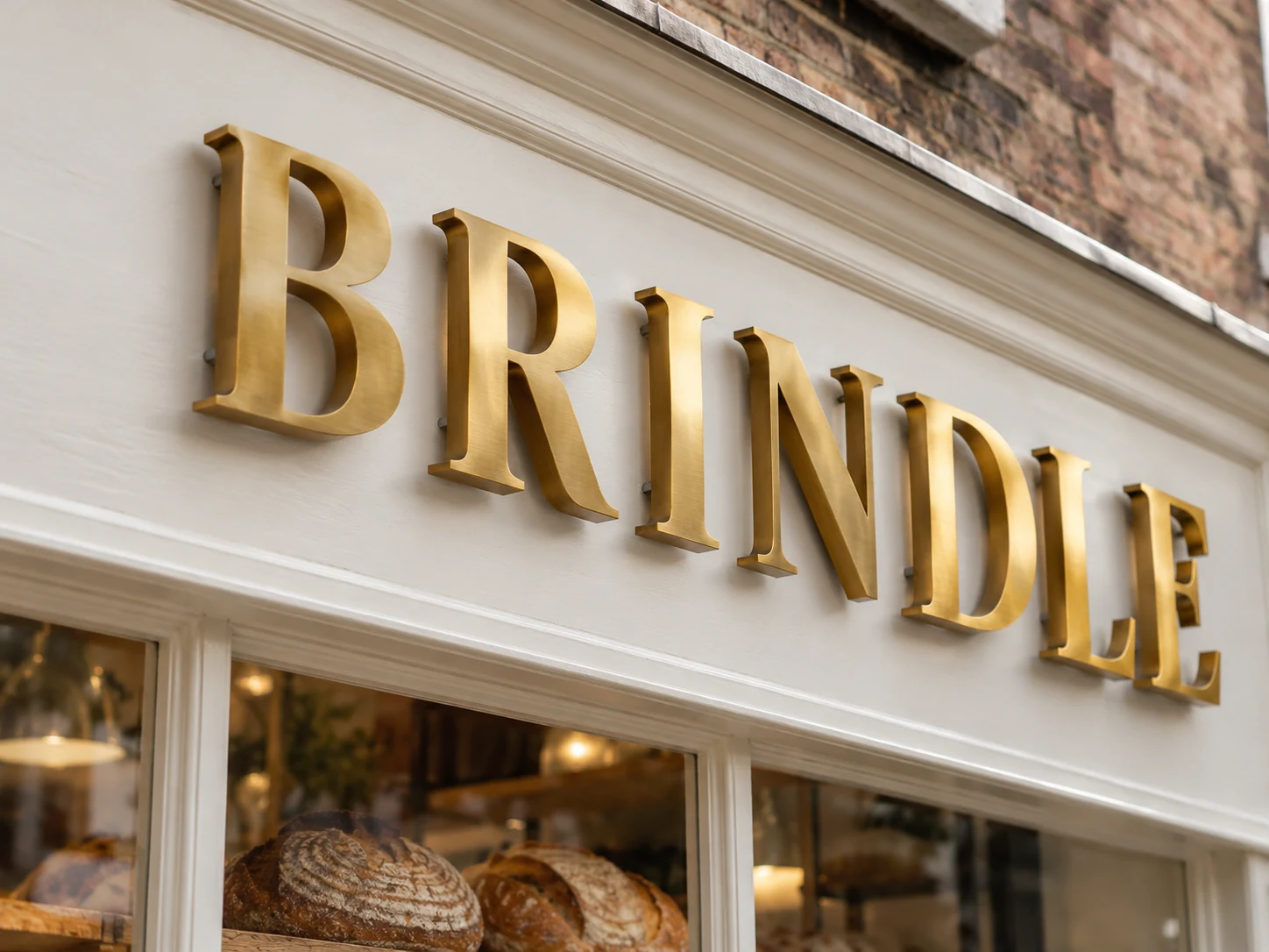 Lion Sign — Brushed brass dimensional lettering for elegant bakery façades and retail branding.